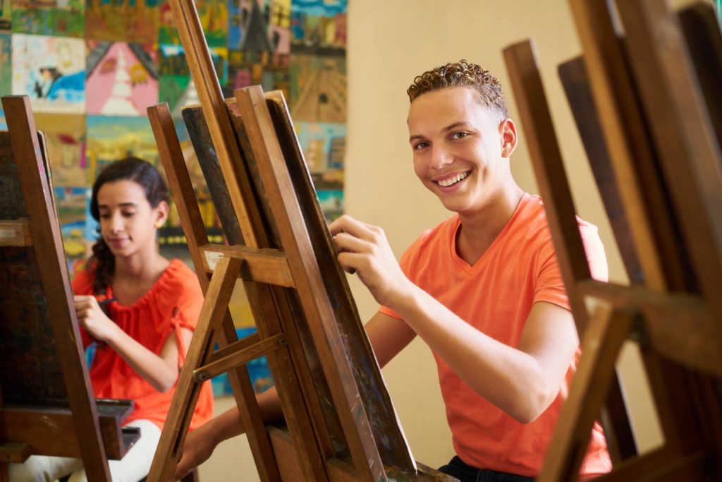 boy working at easel art project smiling