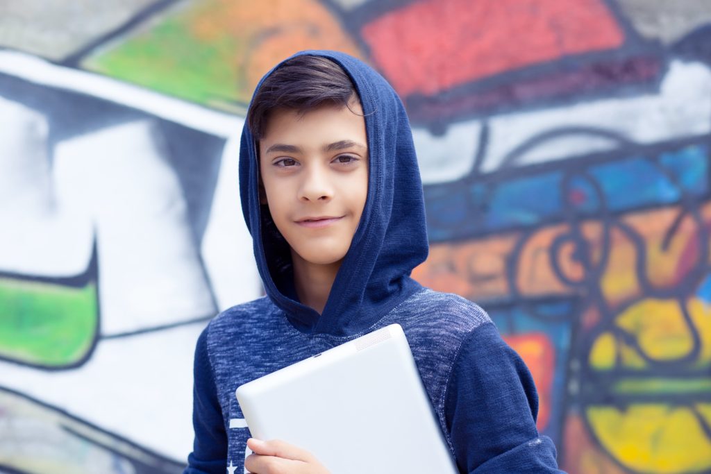 latino boy with laptop smiling against colorful background